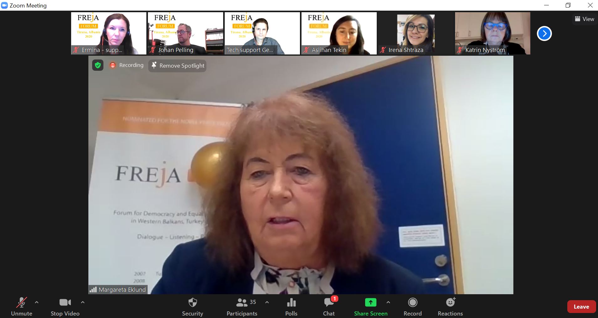 Redhaired woman on digital meeting, Freja poster in background.